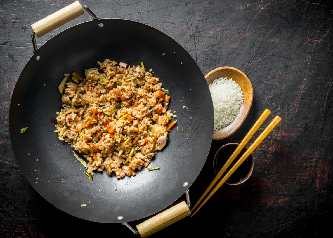 Chinese Wok Cooked Rice In A Wok Pan And Uncooked Rice On A Plate