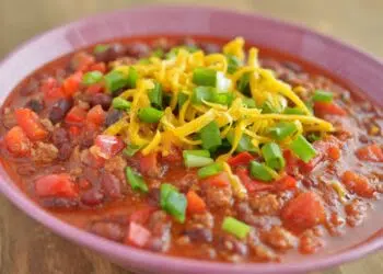 Delicious Venison Chili Recipe In A Red Bowl With Shredded Cheese On Top