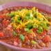 Delicious Venison Chili Recipe In A Red Bowl With Shredded Cheese On Top