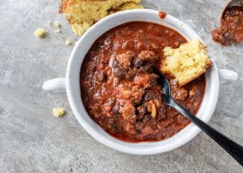 Easy Hearty Beef Chili With Corn Bread On Top In White Bowl
