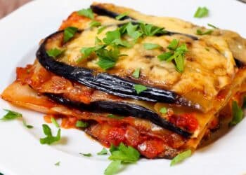 A Slice Of Healthy Primal Lasagna On A White Plate With Garnish