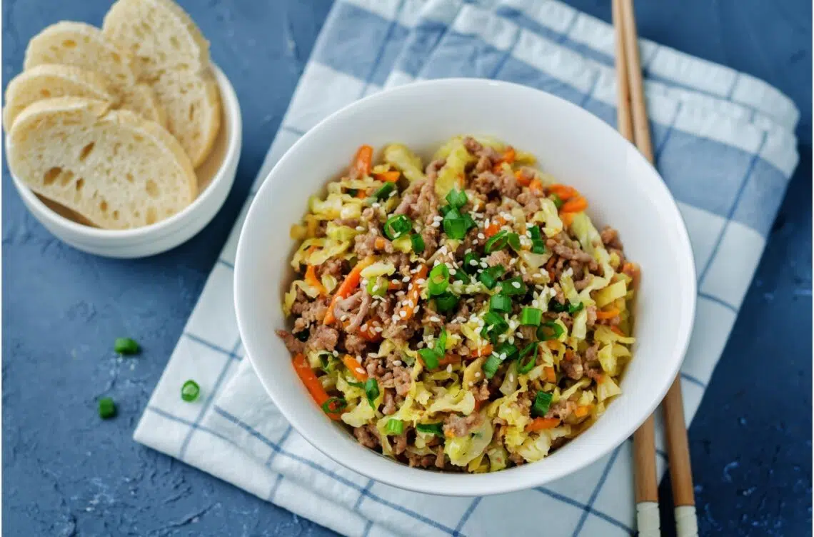 Meat And Cabbage Stir Fry In White Bowl With Slices Of Breads On The Side