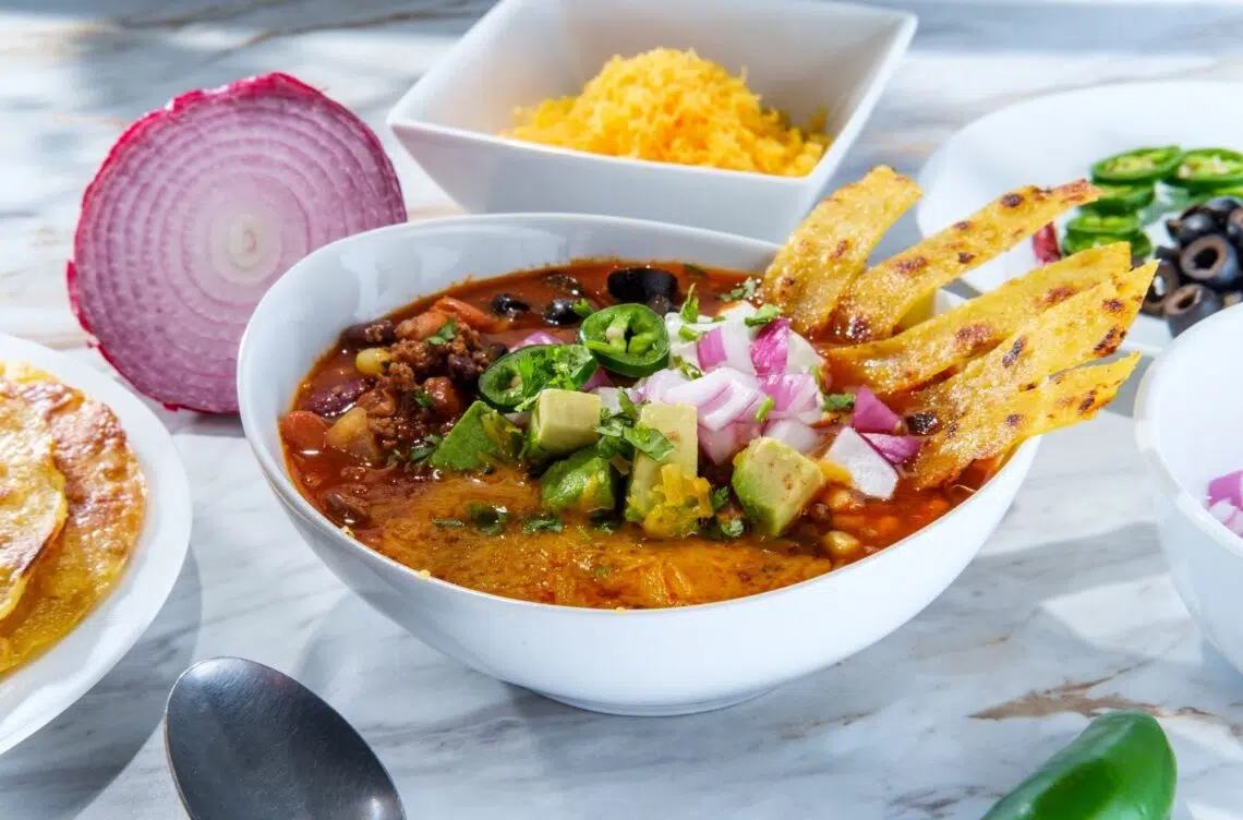 1-Hour Heartwarming Taco Soup Topped With Cheese, Olives, Crushed Tortilla Chips, Avocados And Onions