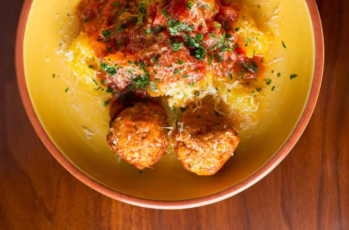 Slow Cooker Healthy Turkey Meatballs Over Spaghetti Squash Served On A Yellow Plate