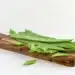 A Group Of Fresh Green Flat Runner Beans On A Wooden Cutting Board, Whole And Sliced