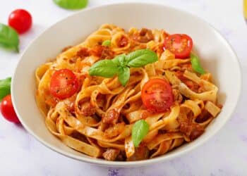 Delicious Homemade Fettuccine Bolognese With Slices Of Tomatoes And Basil Leaves