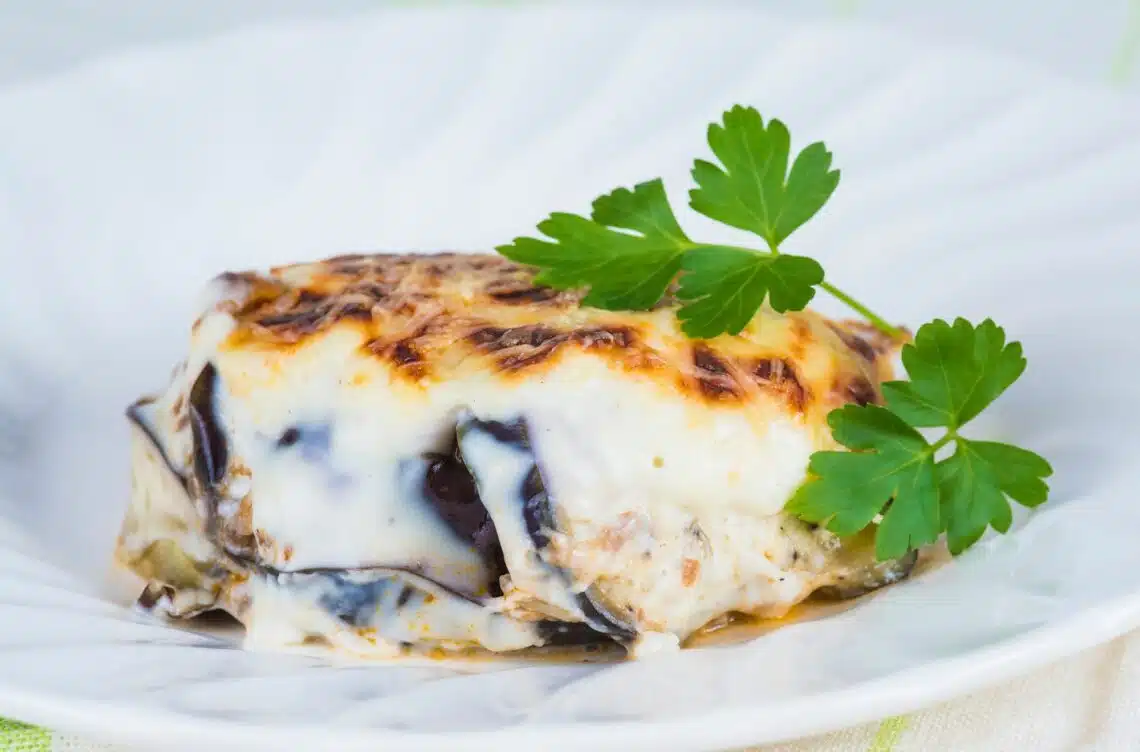 Classic Moussaka Served On A White Plate With Creamy Béchamel Sauce