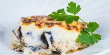 Classic Moussaka Served On A White Plate With Creamy Béchamel Sauce